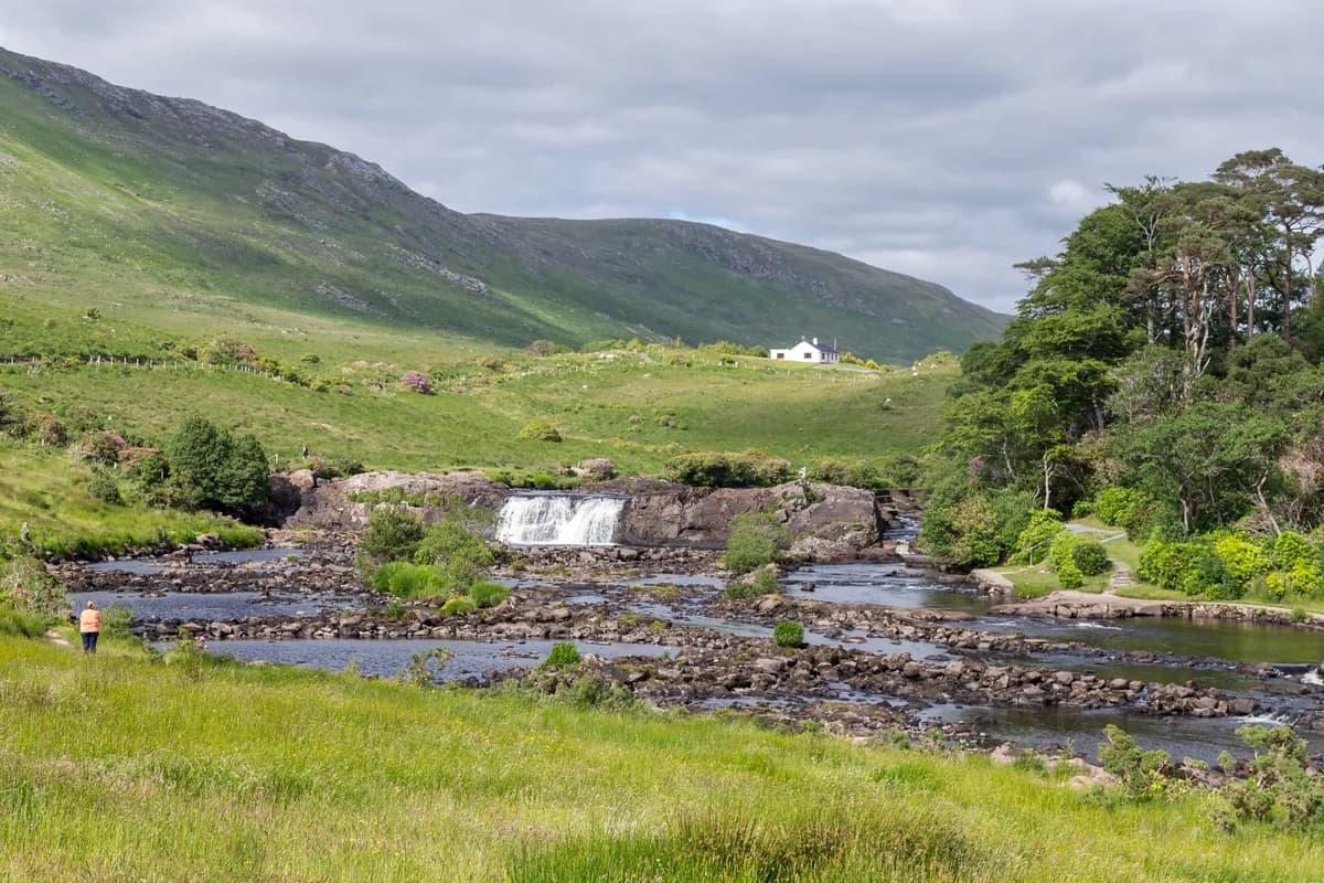 Aasleagh Falls cascading over rocks on the Erriff River with green hills in the background